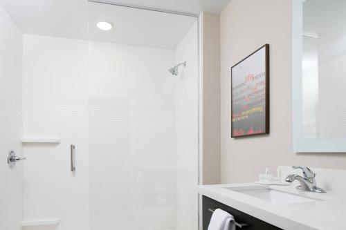 a white bathroom with a sink and a shower at TownePlace Suites by Marriott Kansas City Airport in Kansas City