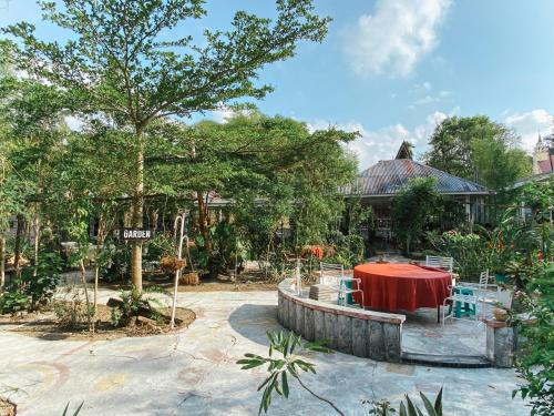 un patio con tavolo e sedie rossi e un edificio di Ruma Kaca Simanindo Bed&Breakfast ad Ambarita