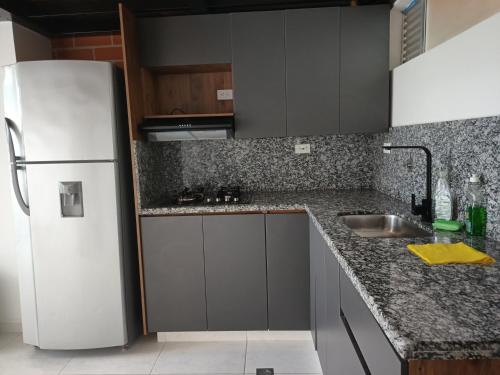 a kitchen with a white refrigerator and a sink at Agradable apartasol duplex in San Jerónimo