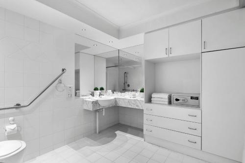 a white bathroom with a sink and a microwave at Melbourne Marriott Hotel in Melbourne