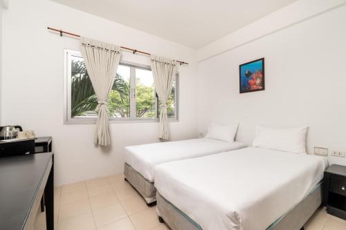 two beds in a white room with a window at PP Charlie Beach Resort- SHA Plus in Phi Phi Don