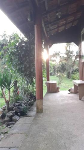 a covered porch with two benches and a tree at CABANA-DAGA in São Francisco do Sul