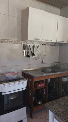 a small kitchen with a stove and a sink at CABANA-DAGA in São Francisco do Sul