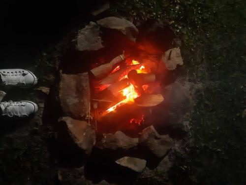 a fire pit in the grass next to a persons feet at CABANA-DAGA in São Francisco do Sul