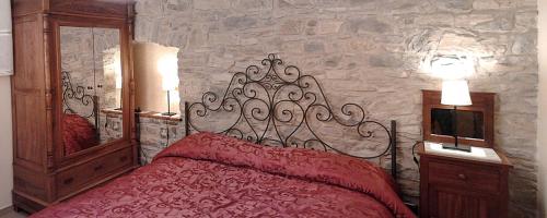 a bedroom with a red bed and a stone wall at Il Baglivo in Agnone