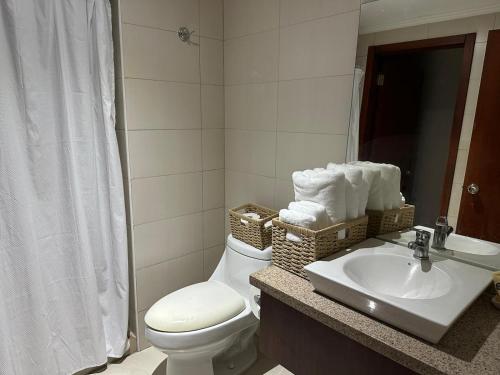 a bathroom with a toilet and a sink with towels at Spacious 2 Bedroom Apartment with river views in Puerto Santa Ana River Front 2 in Guayaquil