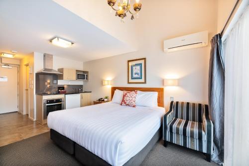 a bedroom with a bed and a chair at Best Western Newmarket Inn & Suites in Auckland