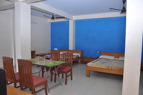 een eetkamer met een tafel en stoelen en een blauwe muur bij Vinayaka Deluxe Lodge in Kushālnagar