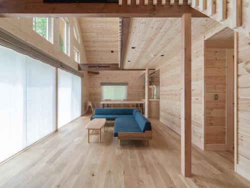 山中湖的住宿－[lamp. Yamanaka] 新築高級デザイナーズ ログハウス 大自然の中でBBQ可！，一间设有蓝色床的卧室,位于带木墙的房间