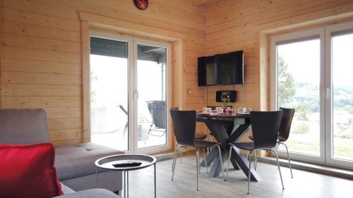 uma sala de estar com uma mesa e cadeiras e uma televisão em WellnessFerienhaus Haus 1 mit Pool, Sauna und eigenem Whirlpool mitten in Deutschland em Wasungen