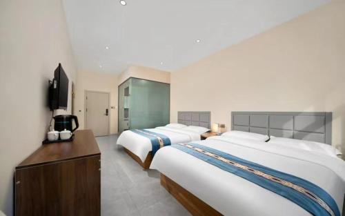 Habitación de hotel con 2 camas y TV en Hongge Hotel - Harbin Taiping Airport en Harbin