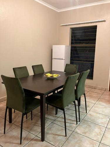 a dining room with a table and green chairs at Secure Townhouse Bedroom Immediately Available in Roodepoort