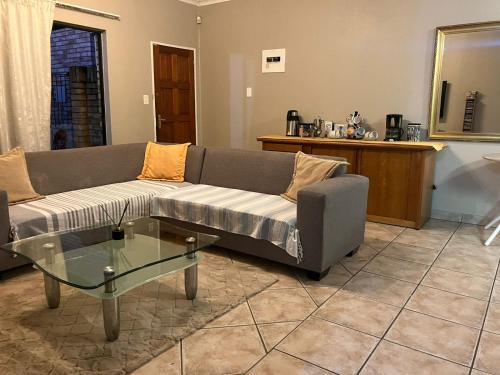 a living room with a couch and a glass table at Secure Townhouse Bedroom Immediately Available in Roodepoort