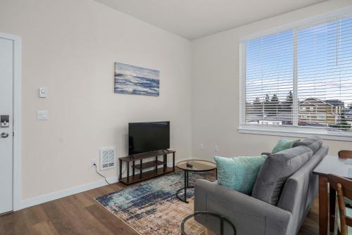 a living room with a couch and a television at Urban Living: Stylish Apts in the Heart of Tacoma in Tacoma