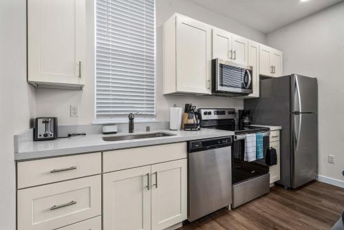 a kitchen with white cabinets and a stainless steel refrigerator at Urban Living: Stylish Apts in the Heart of Tacoma in Tacoma