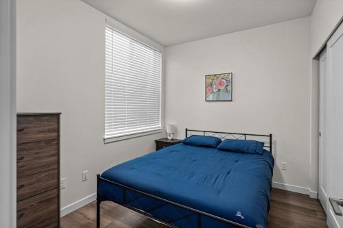a bedroom with a bed with blue sheets and a window at Urban Living: Stylish Apts in the Heart of Tacoma in Tacoma