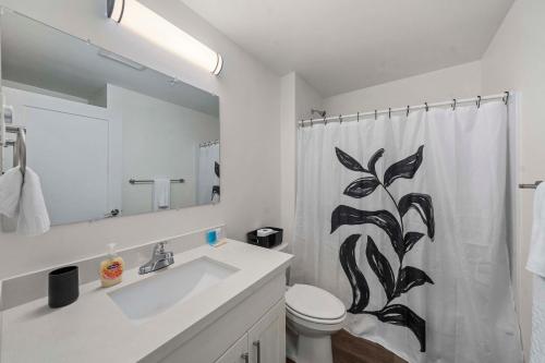 a bathroom with a sink and a toilet and a shower curtain at Urban Living: Stylish Apts in the Heart of Tacoma in Tacoma