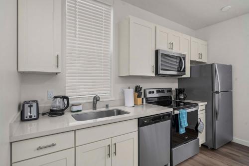 a kitchen with white cabinets and a stainless steel refrigerator at Urban Living: Stylish Apts in the Heart of Tacoma in Tacoma