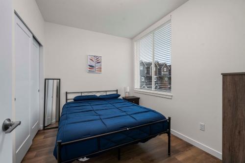 a bedroom with a bed with a blue comforter and a window at Urban Living: Stylish Apts in the Heart of Tacoma in Tacoma