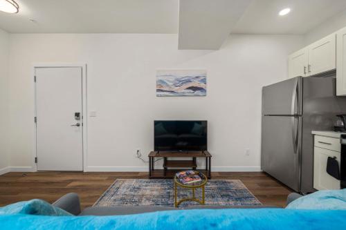 a living room with a refrigerator and a tv at Urban Living: Stylish Apts in the Heart of Tacoma in Tacoma