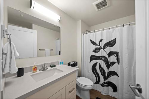 a bathroom with a sink and a toilet and a shower curtain at Urban Living: Stylish Apts in the Heart of Tacoma in Tacoma
