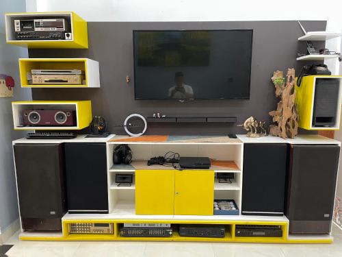 a living room with a tv and a yellow entertainment center at CASA Camping House in Tuy Hoa