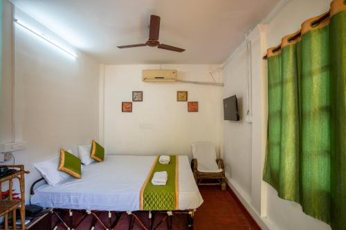 Habitación pequeña con cama y cortina verde en Luigi Villa en Pondicherry