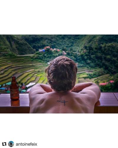 a man with a cross tattoo on his back looking out a window at Batad Hillside Inn and Restaurant in Banaue
