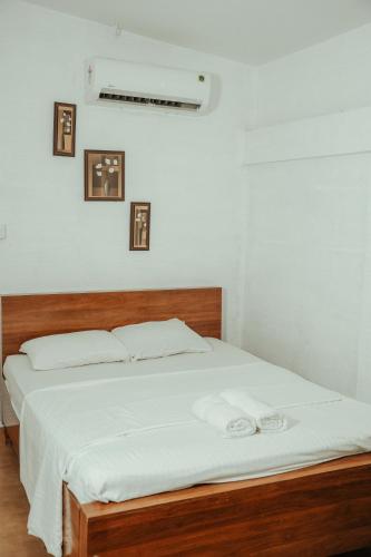 a bedroom with a bed with white sheets and pictures on the wall at Waves and Shores Beach Villa in Mararikulam