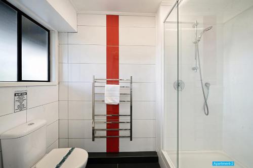 a bathroom with a toilet and a red stripe on the wall at Maison de Rose in Auckland