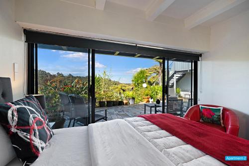 um quarto com uma cama e uma grande janela de vidro em Maison de Rose em Auckland