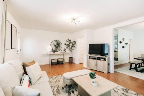 ein Wohnzimmer mit einem weißen Sofa und einem TV in der Unterkunft Bright, chic & spacious in the heart of St. Paul by Summit-University with porch and swing chairs in Saint Paul