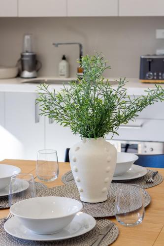 a table with a white vase with a plant in it at Luxury Without Limits in CBD Christchurch in Christchurch