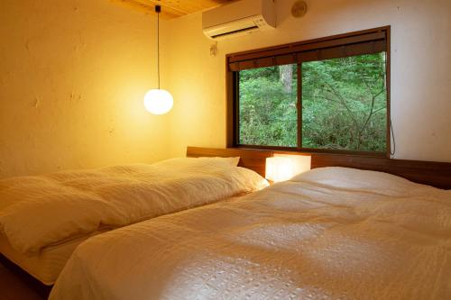 two beds in a bedroom with a window at kamenos Luxury Resort With Beautiful Scenery Hiji in Hiji