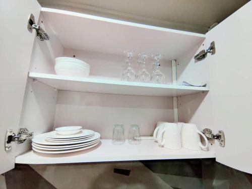 a white shelf with plates and glasses on it at Studio at Berry Road in Suva