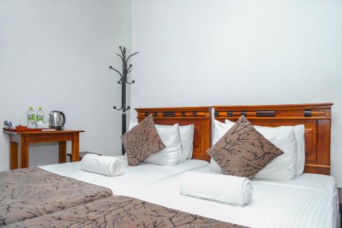 a bedroom with a large bed with white and brown pillows at Kandy Tower Inn in Kandy