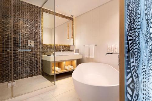 a bathroom with a tub and a sink and a shower at Lagos Marriott Hotel Ikeja in Lagos
