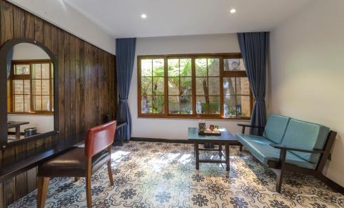 a living room with a table and a bench and windows at Brick House Dalat Hotel in Da Lat
