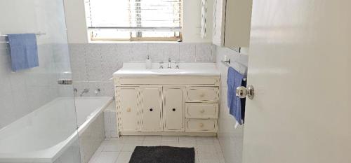 baño blanco con lavabo, bañera y tubermott en Peaceful House en Perth