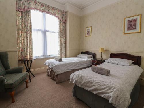 a bedroom with two beds and a chair and a window at Ryburn Lodge in Bridlington