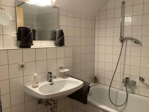 La salle de bains est pourvue de carrelage blanc, d'un lavabo et d'une douche. dans l'établissement Haus Rieslehof Apartment 11, à Titisee-Neustadt