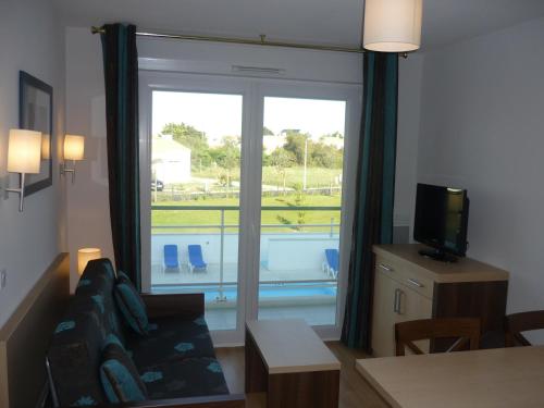 a living room with a couch and a large window at Résidence Goélia La Grande Plage in Saint-Gilles-Croix-de-Vie