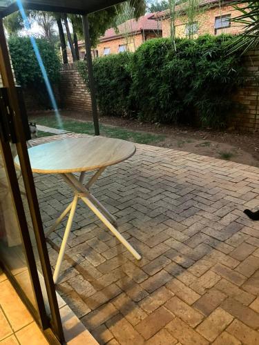 a wooden table and a chair under an umbrella at Secure Townhouse Bedroom Immediately Available in Roodepoort