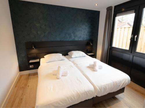 um quarto com uma grande cama branca e 2 almofadas brancas em Wellness Bungalow with whirlpool and sauna em Zevenhuizen