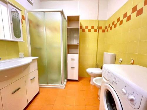 a bathroom with a shower and a toilet and a washing machine at Inviting apartment by the beach in Porto Santa Margherita di Caorle
