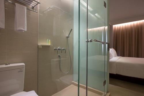 فندق Santika Premiere Hayam Wuruk Jakarta في جاكرتا: حمام مع دش زجاجي مع مرحاض