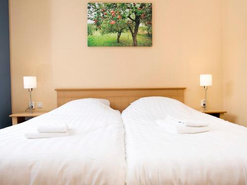 ein Schlafzimmer mit einem weißen Bett und einem Gemälde an der Wand in der Unterkunft Nice holiday home with garden in Zevenhuizen