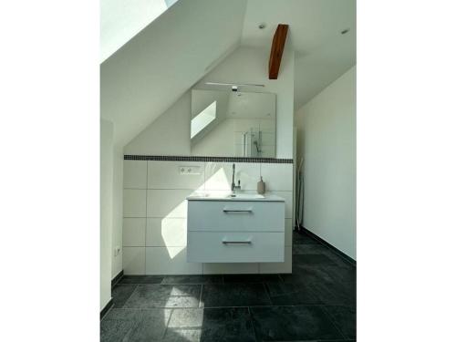 uma casa de banho branca com um lavatório e um espelho em Fischerstuv Modern retreat em Tönning