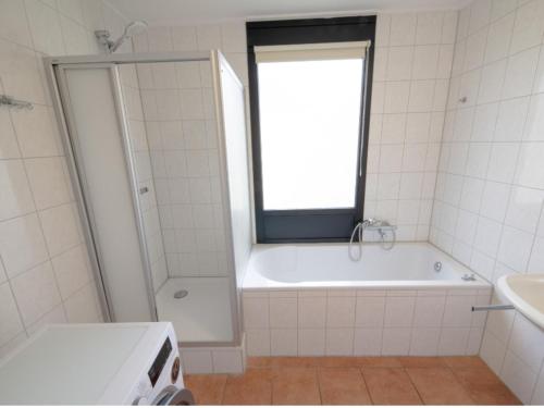 a bathroom with a tub and a window and a sink at Premium bungalow 6 persons in Zevenhuizen