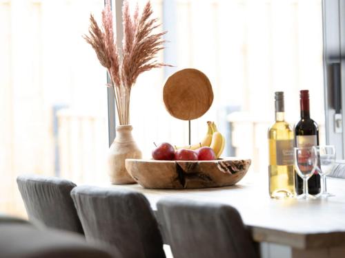a bowl of fruit on a table with bottles of wine at Holiday Home in Zevenhuizen with Sauna Bubble Bath in Zevenhuizen